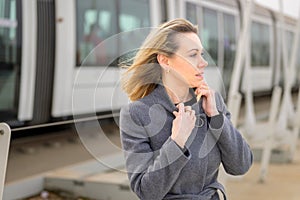 Woman in overcoat walking along a platform at a station