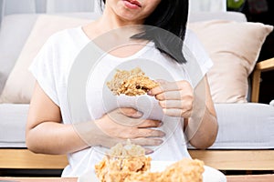 Asian woman overeating fried chicken have a stomachache, indigestion because of eating too much, or binge eating disorder photo