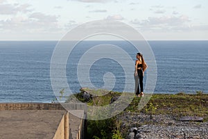 Woman Overlooking Ocean from Cliff Edge