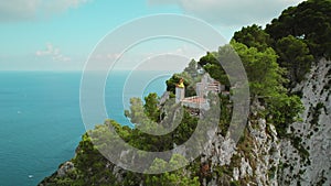 Woman overlooking the Tyrrhenian Sea from Capri Island. Female meditates on rocky edge in summer sunny day. Girl