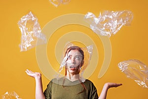 Woman overwhelmed by plastic waste and suffocating from plastic bag over her head - ecology and pollution concept