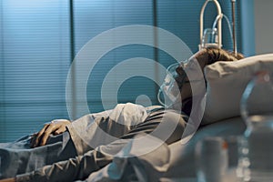 Woman with oxygen mask lying in a hospital bed photo