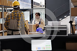 Woman package handler putting cardboard box on table