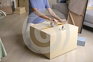 Woman packing box preparing for house moving.