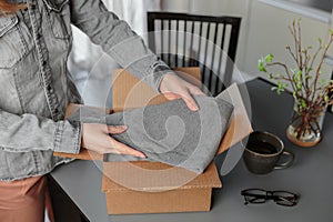 Woman packing box with used wardrobe for resale