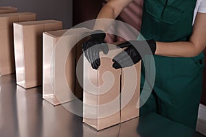 Woman packing cardboard boxes at production line, closeup
