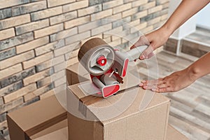 Woman packing carton box indoors, closeup