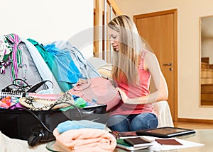 Woman packing clothes and accessories into suitcase