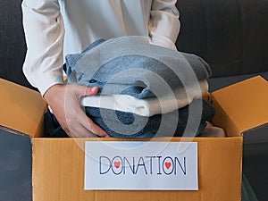 Woman packing clothes into a cardboard box for donation