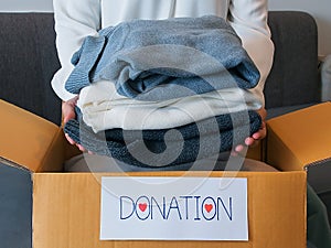 Woman packing clothes into a cardboard box for donation