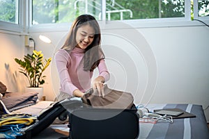 Woman Packing clothes into luggage at home, preparing to travel