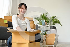 Woman packing her stuff in a cardboard boxes, preparing parcel for relocate