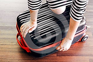 Woman packing a luggage on wooden floor