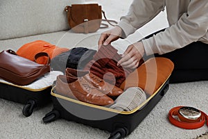 Woman packing suitcase for trip at home, closeup
