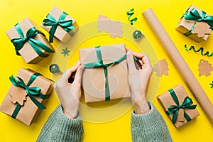 Woman is packing surprise gift for Christmas holidays, sitting at workplace with craft tools, top view. Woman wrapping