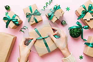 Woman is packing surprise gift for Christmas holidays, sitting at workplace with craft tools, top view. Woman wrapping