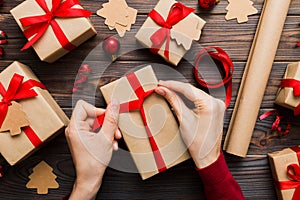 Woman is packing surprise gift for Christmas holidays, sitting at workplace with craft tools, top view. Woman wrapping