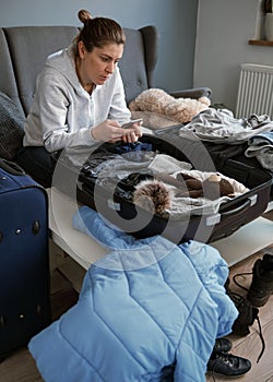 A woman packing things in a suitcase.