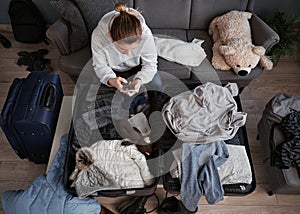 A woman packing things in a suitcase.