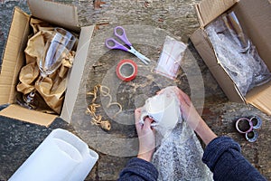 A woman packs a glass cup in a plastic bubble wrap. Fragile package