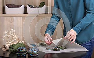 A woman packs recycled accessories in eco-friendly packaging in a home workshop