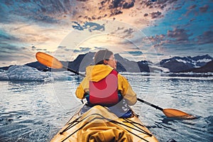 Woman paddle a canoe on an icy bay in Alaska exploring glaciers.