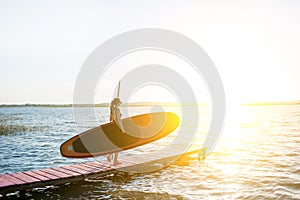 Woman with paddleboard on the pier outdoors