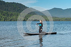 Woman paddleboarding on the mountain lake photo