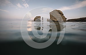 Woman paddleboarding through passage between sea rocks