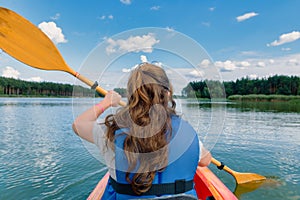 Woman paddles a kayak across a lake