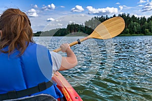 Woman paddles a kayak across a lake