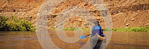 Woman paddling canoe on desert river