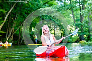 Woman paddling with canoe on forest river