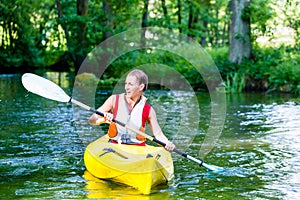 Woman paddling with canoe on forest river