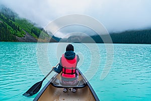 Woman paddling a canoe through Lake Louise