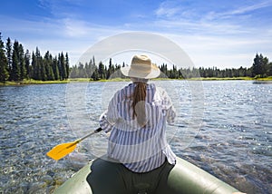 Woman paddling on an inflatable raft while floating the Snake River in Island Park, Idaho on an adventure vacatio