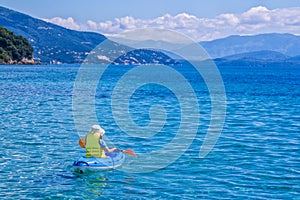Woman paddling kayak in a calm sea bay with turquoise water