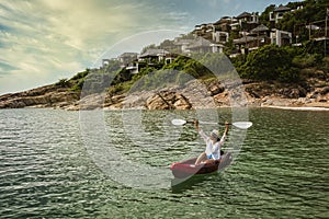 Woman paddling a kayak to exploring calm tropical bay with limestone mountains in