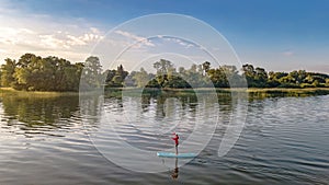 Woman paddling on SUP board on beautiful lake aerial drone view with reflections from above. Standing up paddle boarding adventure