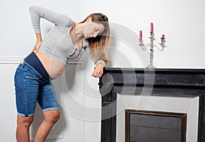 Woman in pain holding head and back near fireplace