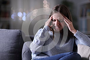 Woman in pain suffering migraine at night at home