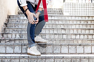 Woman with painful knee struggle walking down flight of stairs