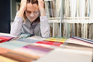 Woman painfully thinks about which fabric to choose in store