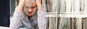 Woman painfully thinks about which fabric to choose in store