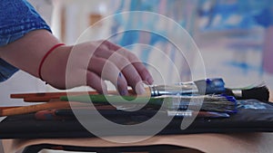 A woman paint artist drawing an abstract blue painting with brushes