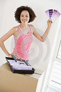 Woman with paint swatches in new home smiling