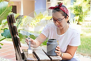 Woman With Paint Upcycling Chair At Home