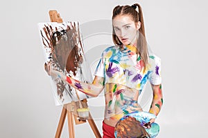 woman painter soiled in colorful paint draws on canvas.