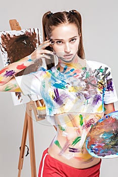 woman painter soiled in colorful paint draws on canvas.