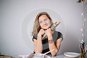 Woman painting clay pot with senior potter at workshop